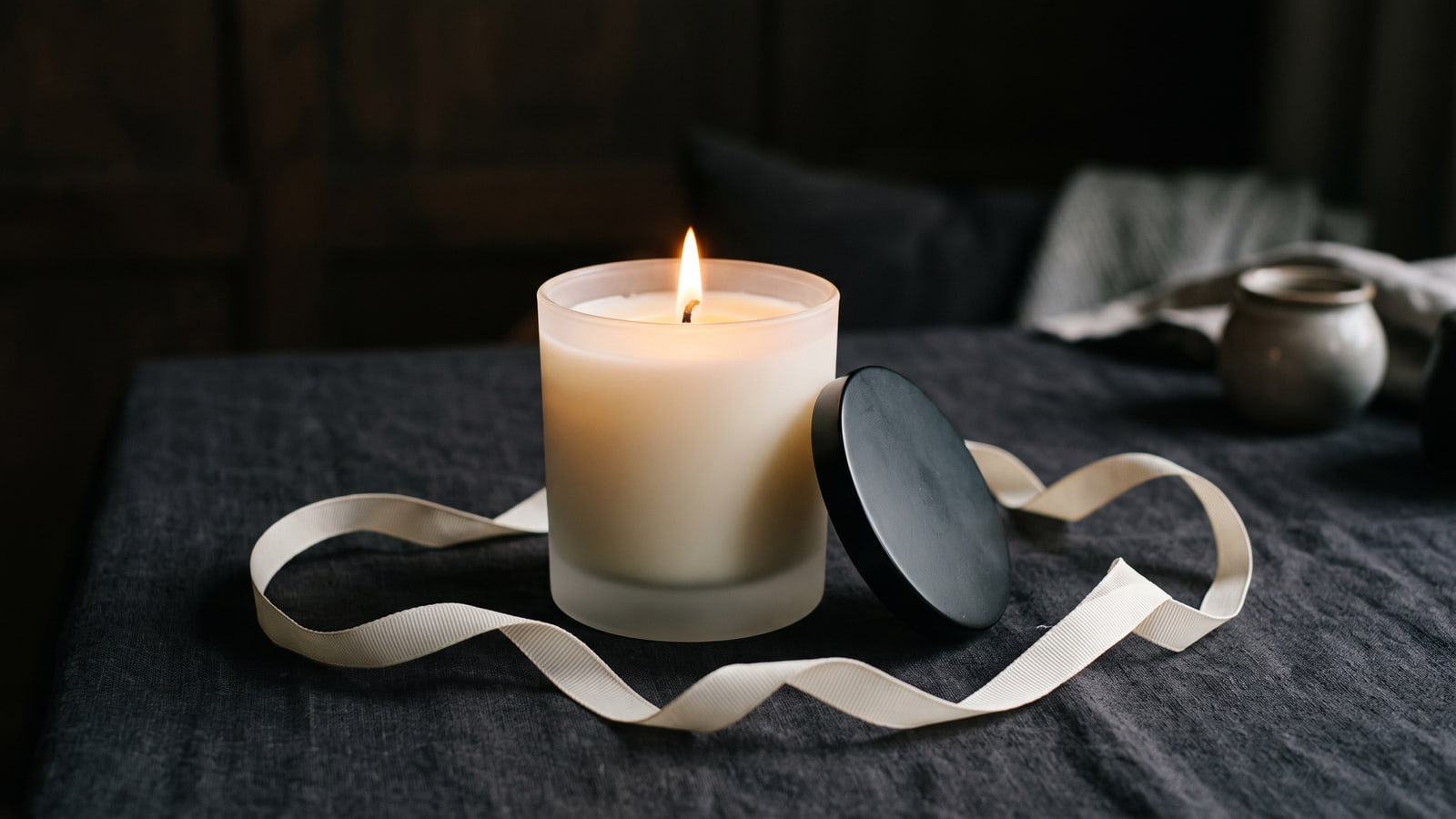 Jo Malone London style cream glass candle beside a gift ribbon