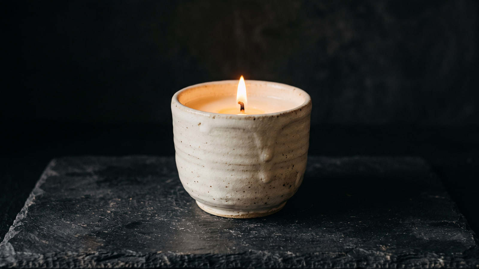 Lumond handcrafted ceramic candle lit on a dark stone surface